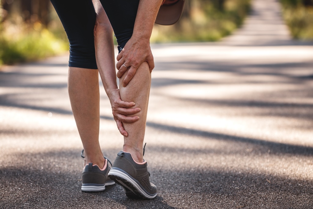 Woman runner holding back of leg from cramp.