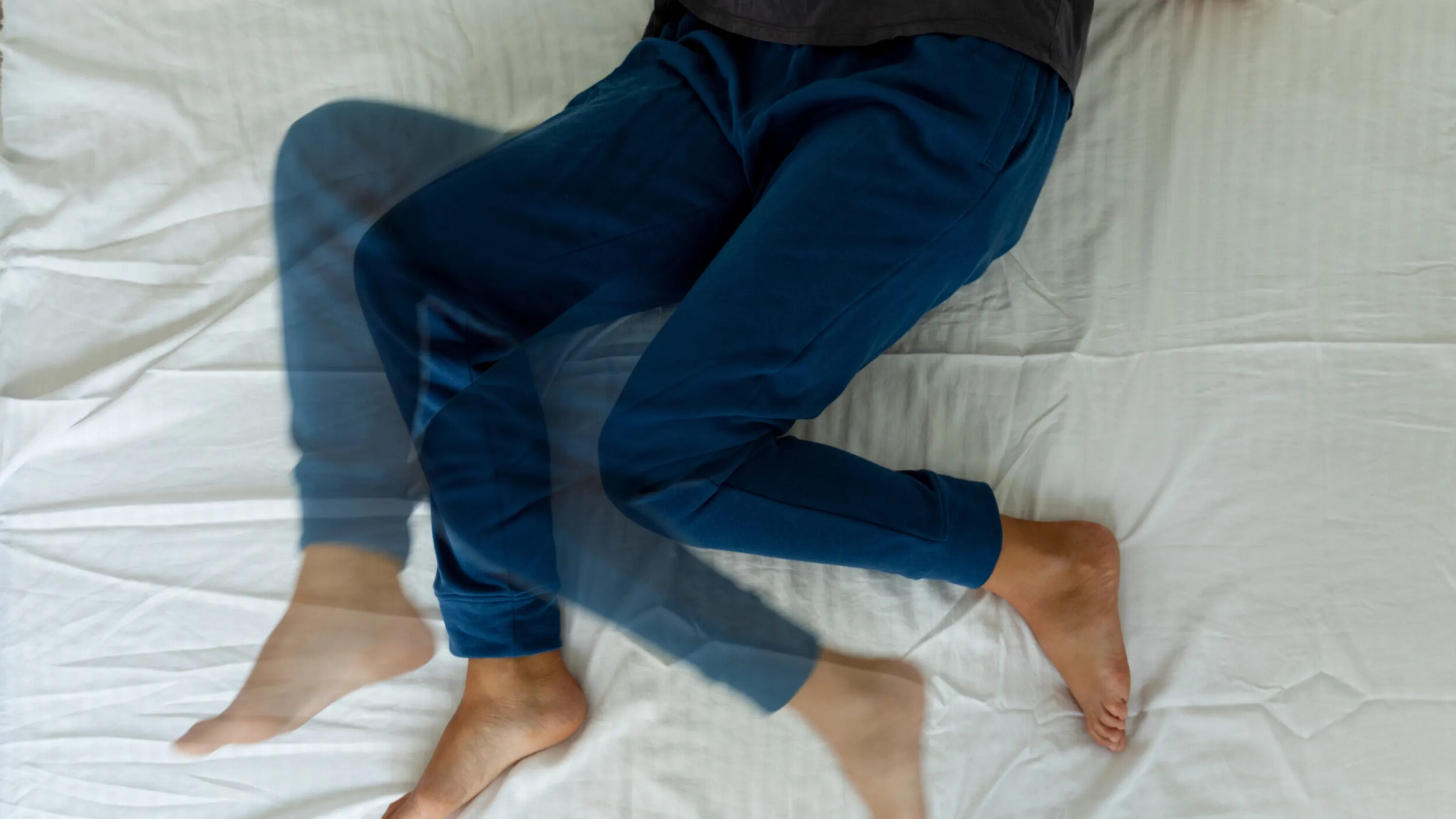 Cropped shot of woman with restless leg syndrome in bed